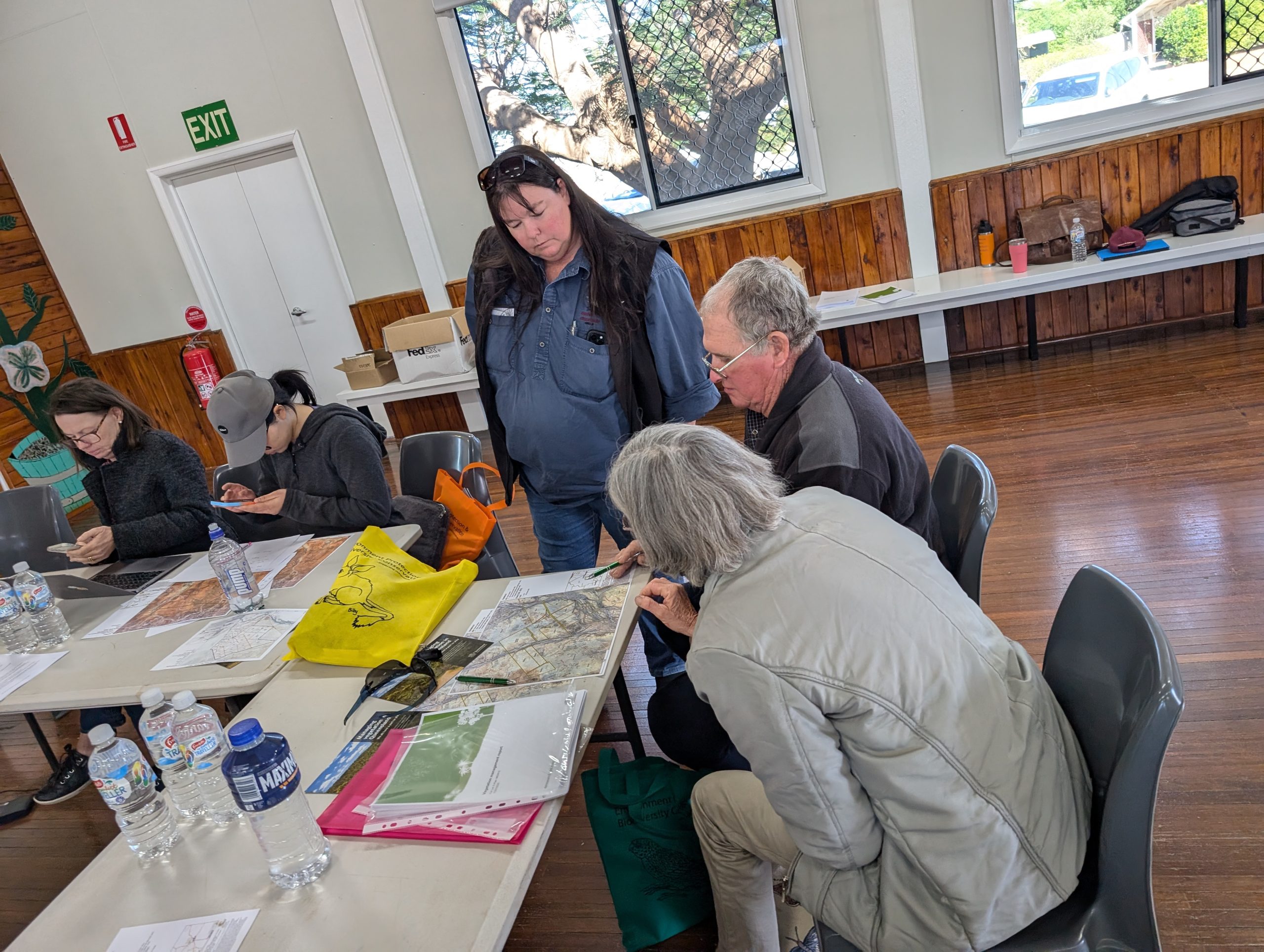Stonehenge Vege Management Workshop (2) A DCQ staff member assists an older landholder couple who are holding several maps of their property.