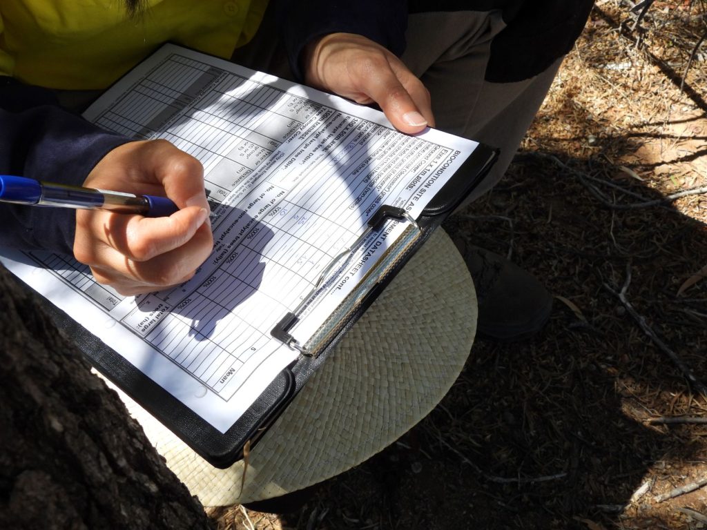 A paper form on a clipboard with numbers next to different categories, such as 'annual grass' and 'leaf litter'.